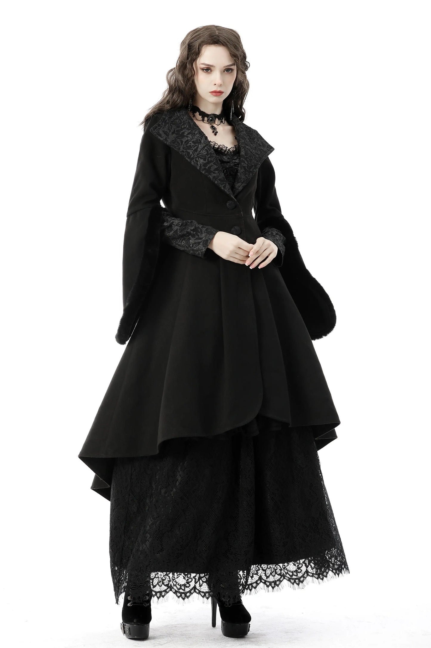 Woman wearing a black gothic-style dress with lace details on a white background