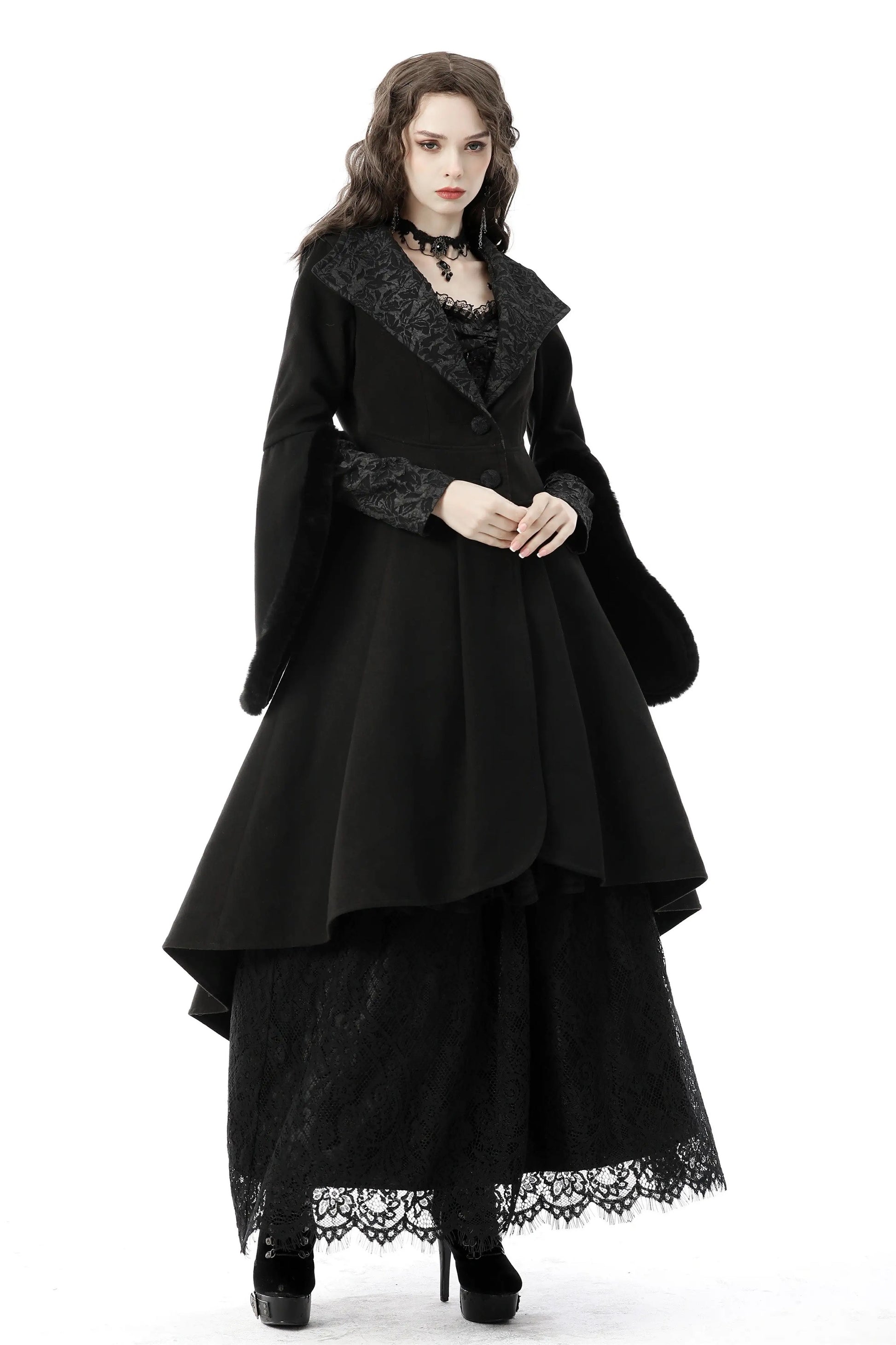 Woman wearing a black gothic-style dress with lace details on a white background