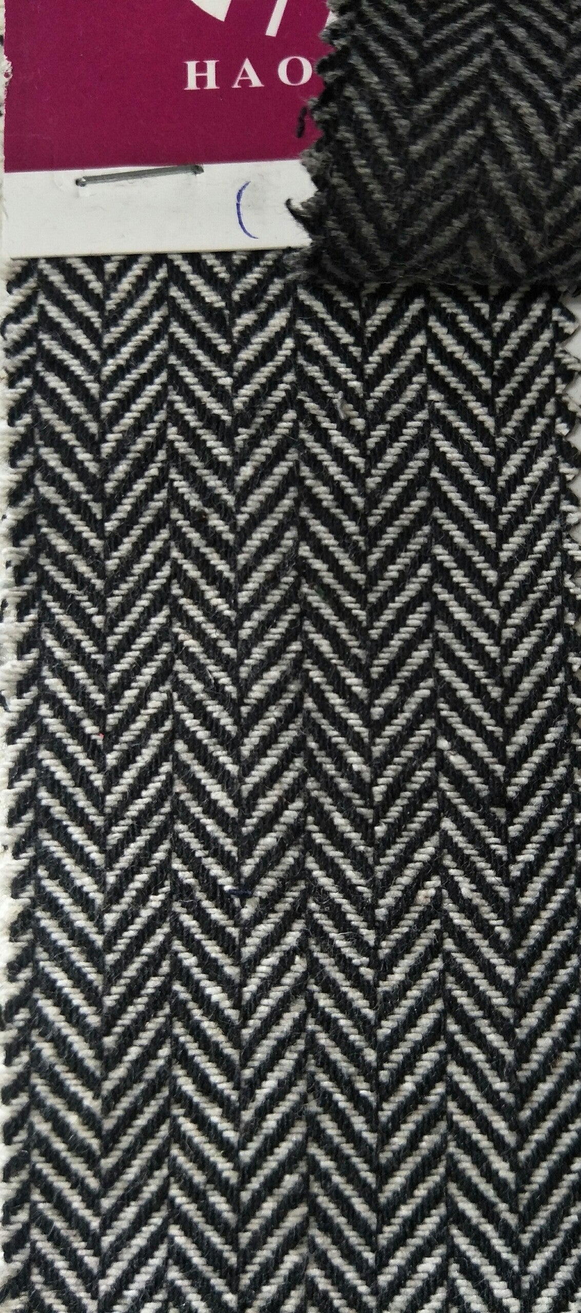 Herringbone pattern fabric swatch with a visible brand label.
